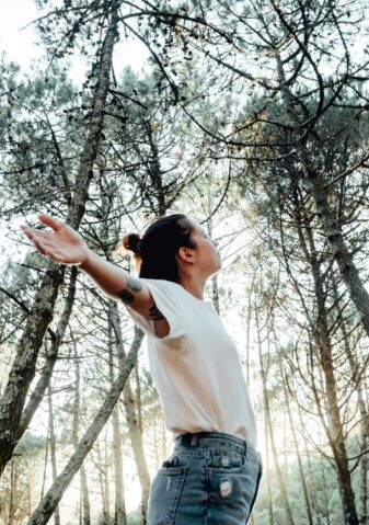young woman breathing clean air in nature forest.Fresh outdoor, wellness healthy lifestyle concept